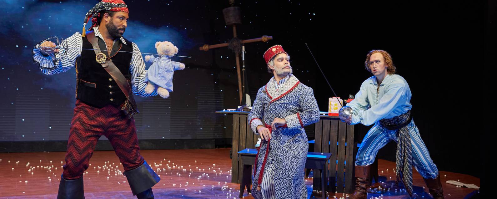Two pirates duel with swords (and one stray teddy bear) in a scene from The Pirates of Penzance.