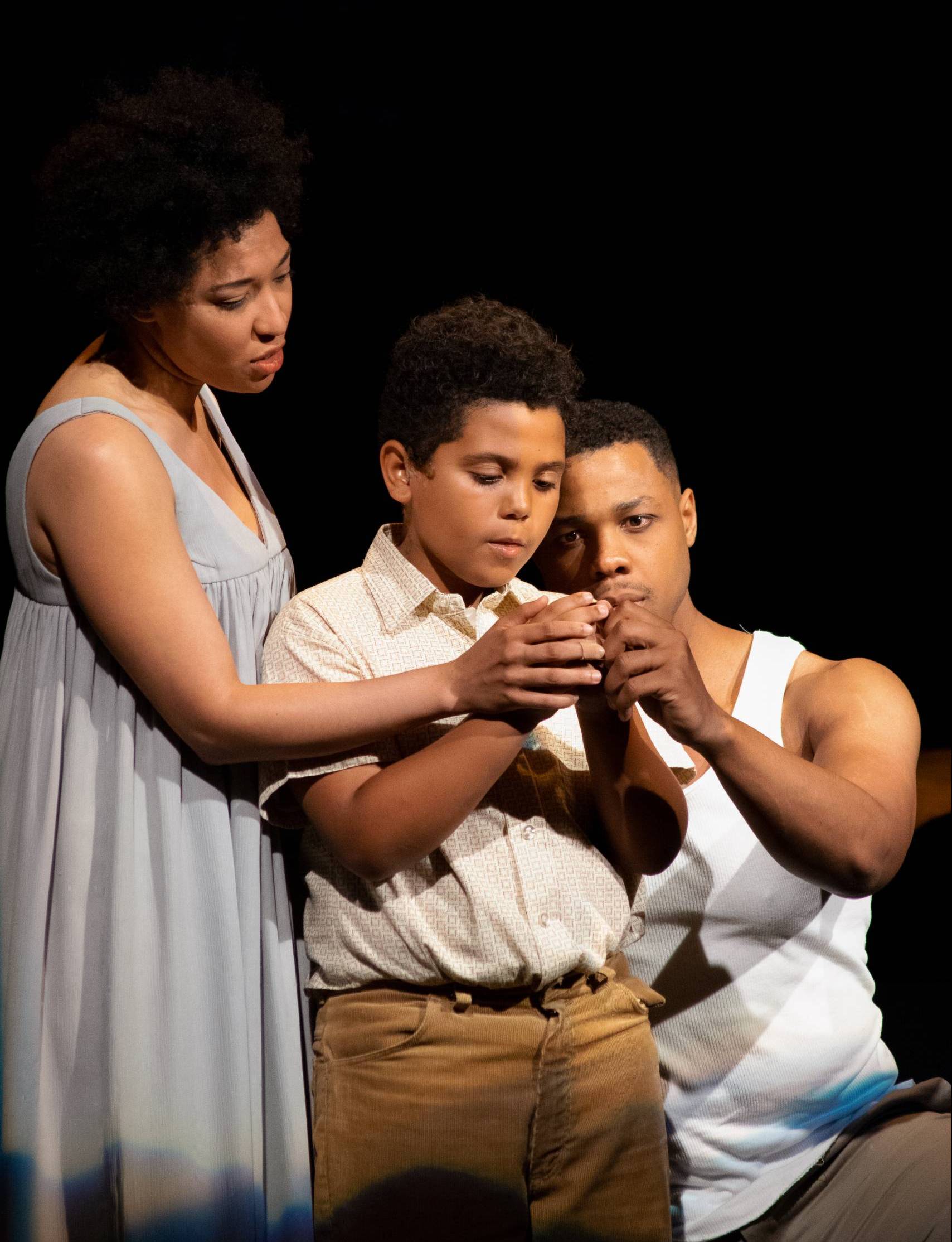 Julia Bullock, Jeremy Denis, and Davone Tines hold up a golden button in Fire Shut Up in My Bones (2019).