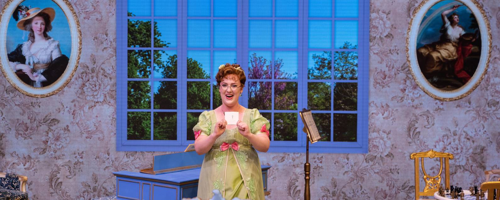 Meridian Prall (Rosina) holds up a cup of tea in front of a beautiful window during The Barber of Seville.