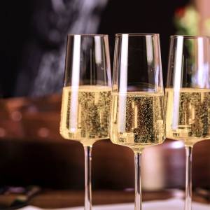 Champagne bubbles away in three glass flutes.